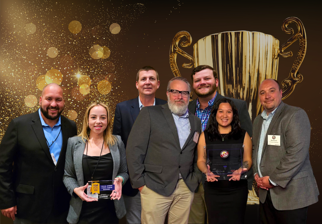 7 employees standing and smiling while holding award plaques
