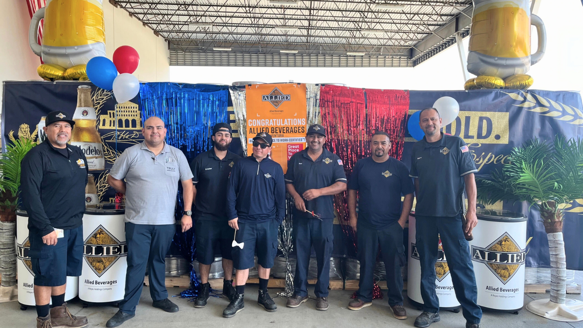 Group of people smiling in front of a workplace award backdrop