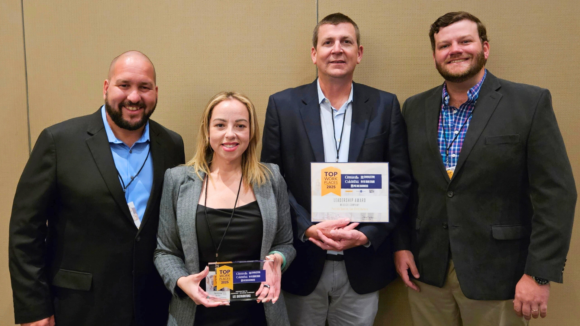 Four people smiling while holding Top Workplaces award