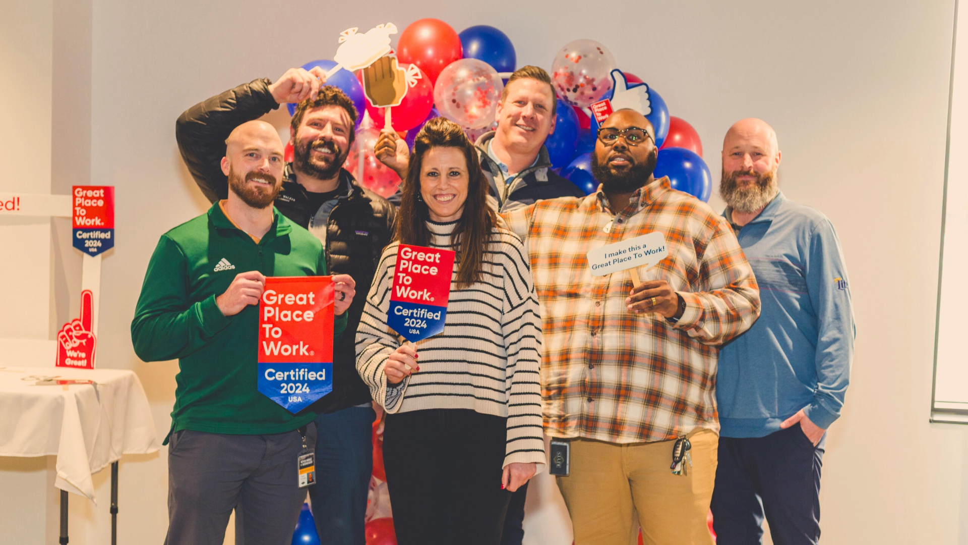 Group of people smiling in front of a workplace award backdrop