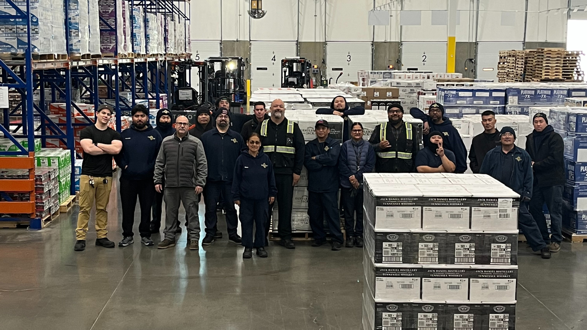 Group of warehouse employees in a warehouse standing near cases of Gentleman Jack