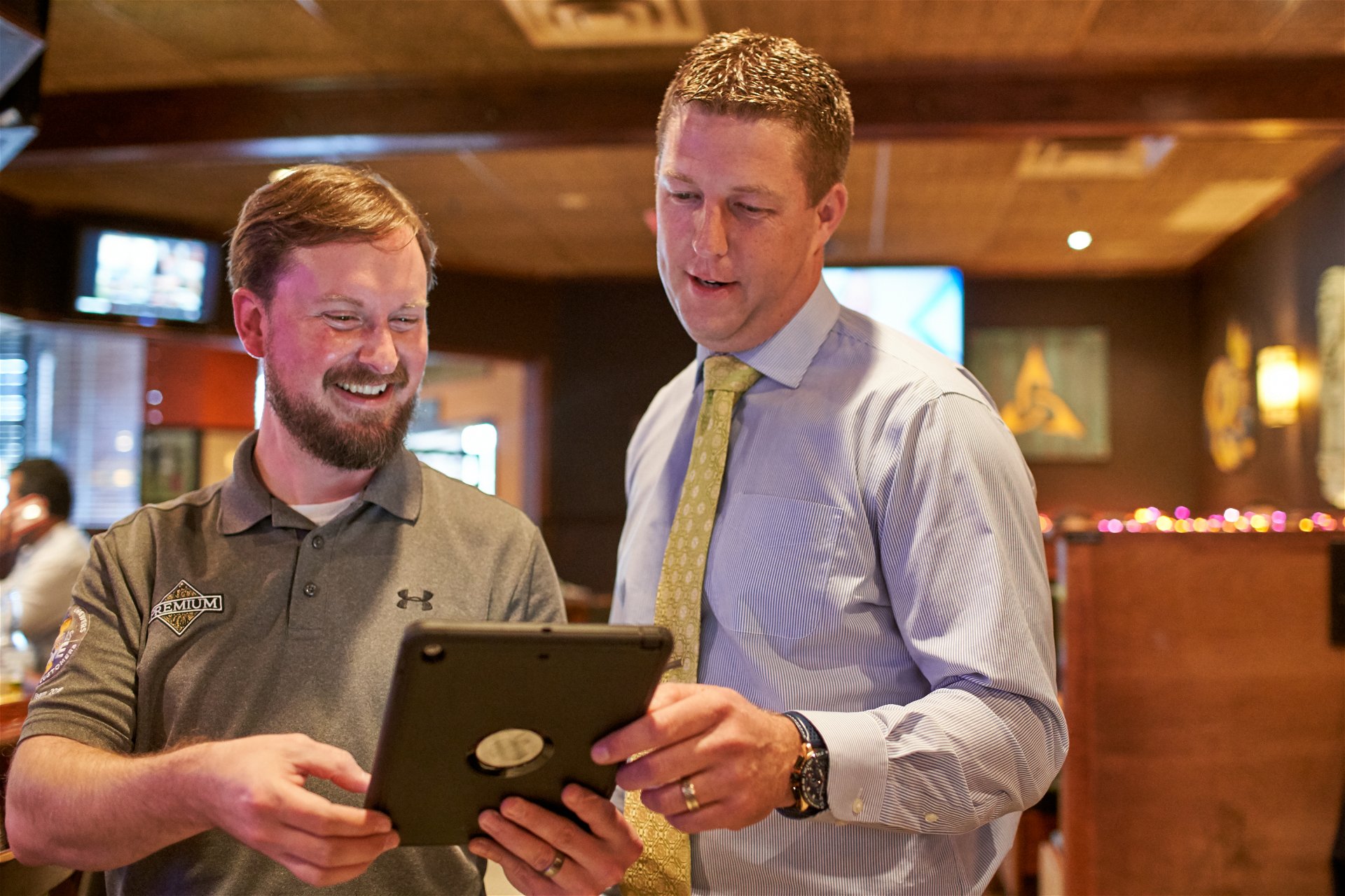 Sales representative looking at an iPad with a business owner in a restaurant