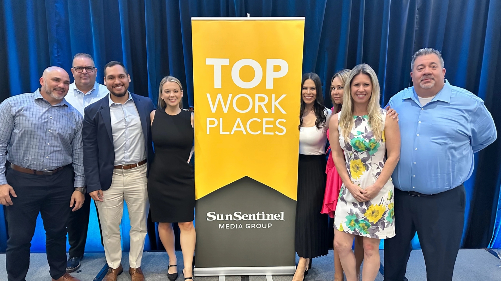 employees pose next to top workplaces sign