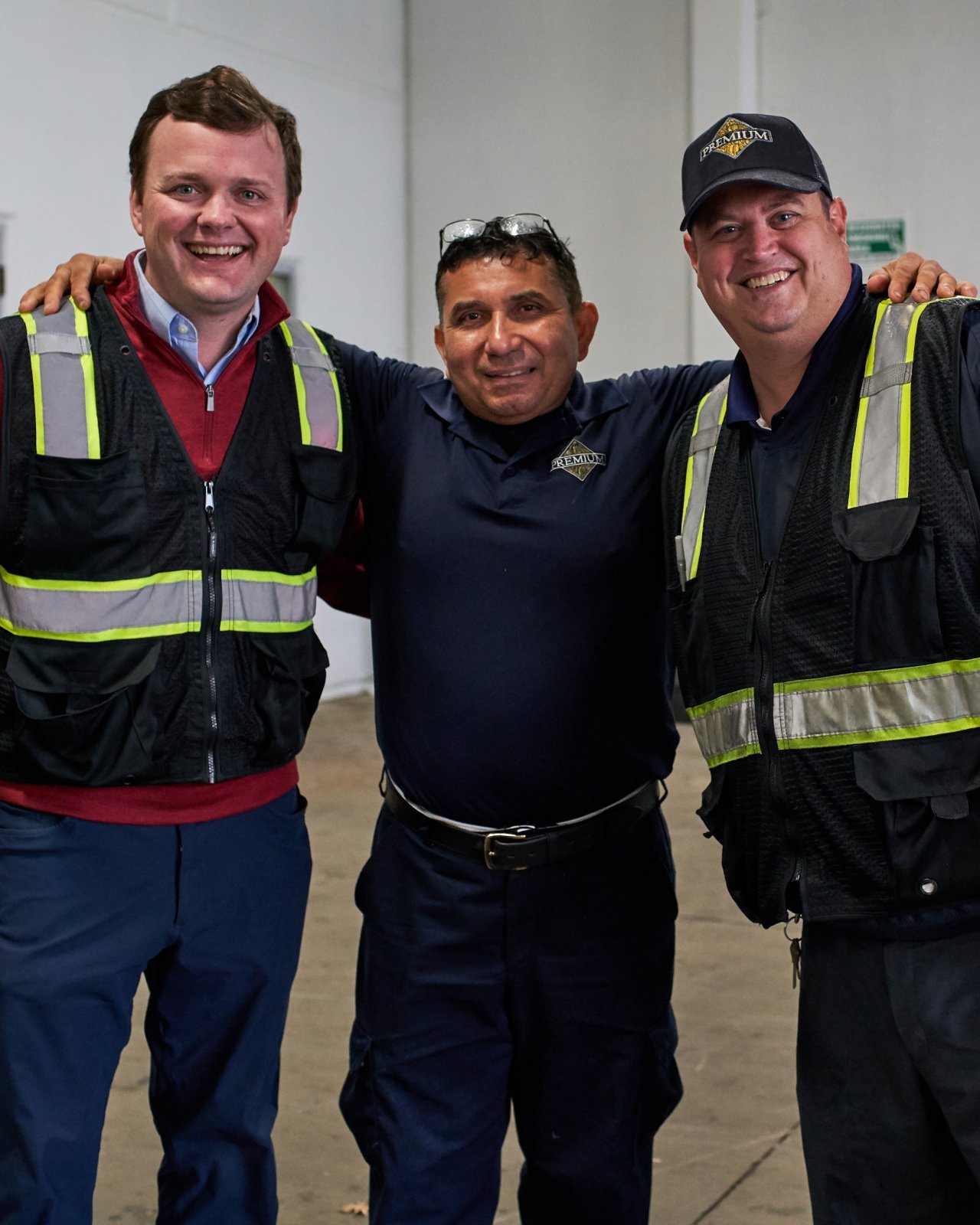 Three warehouse workers standing together for a photo and smiling